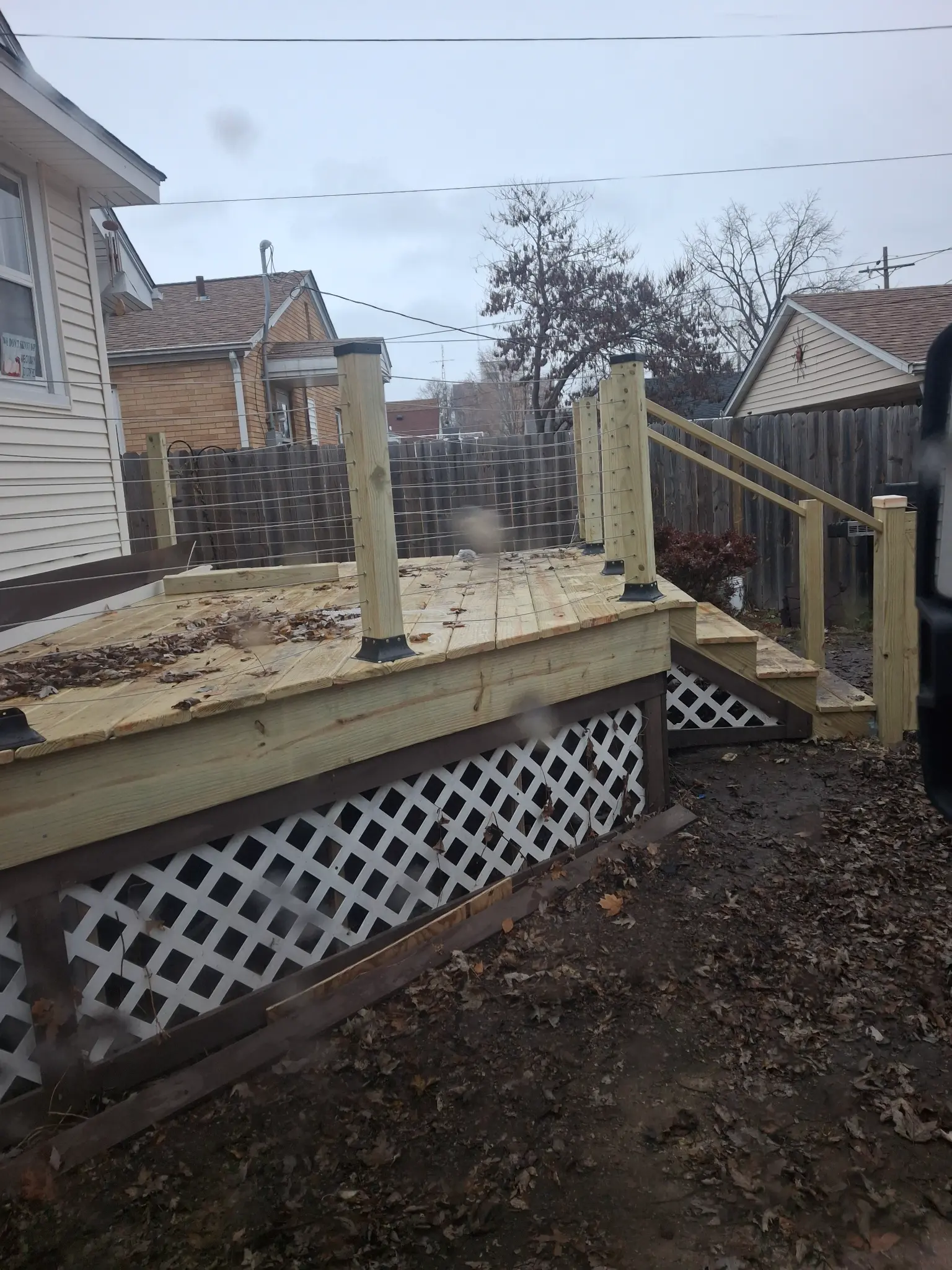 After: Completed pressure-treated deck with cable wire railing, steps, and lattice skirting