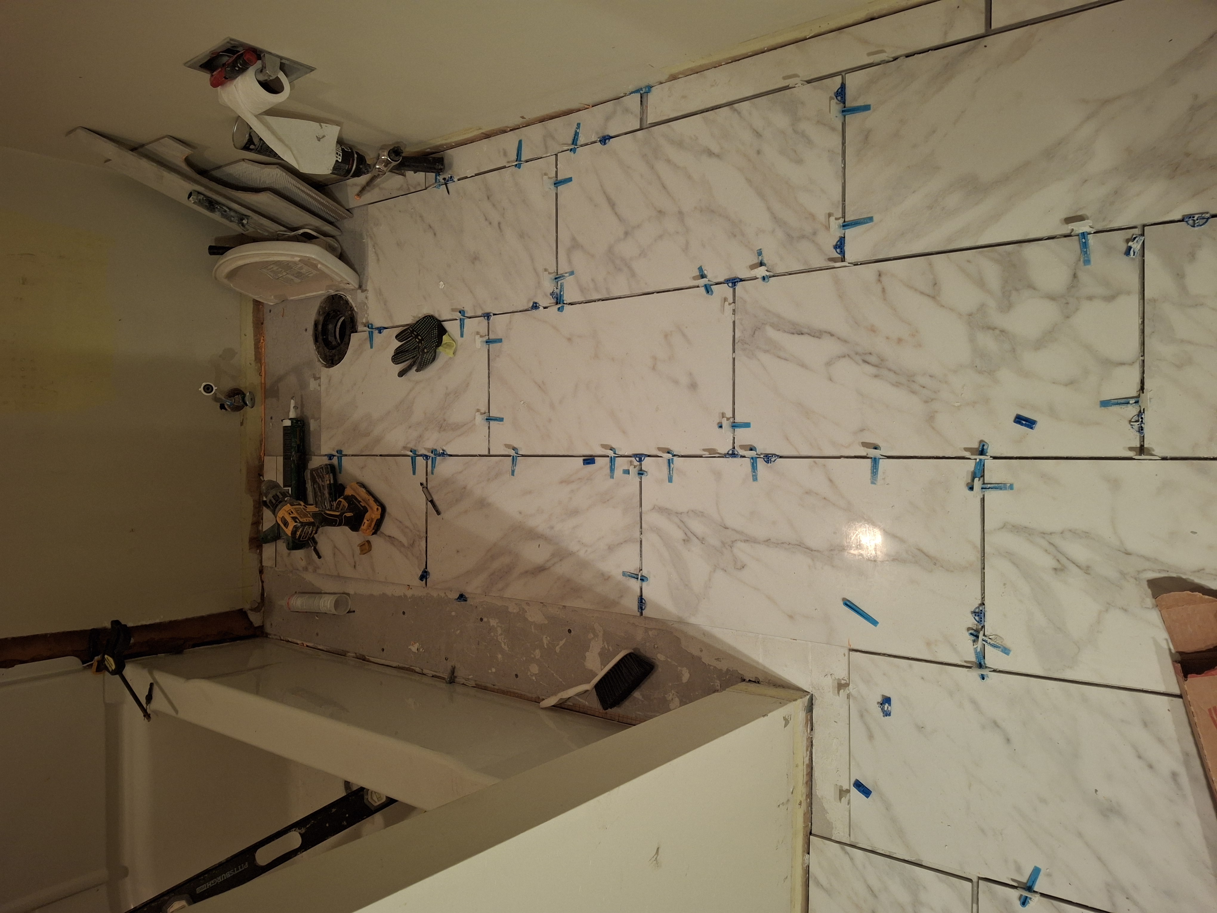 Marble-look bathroom floor tile installation with leveling clips